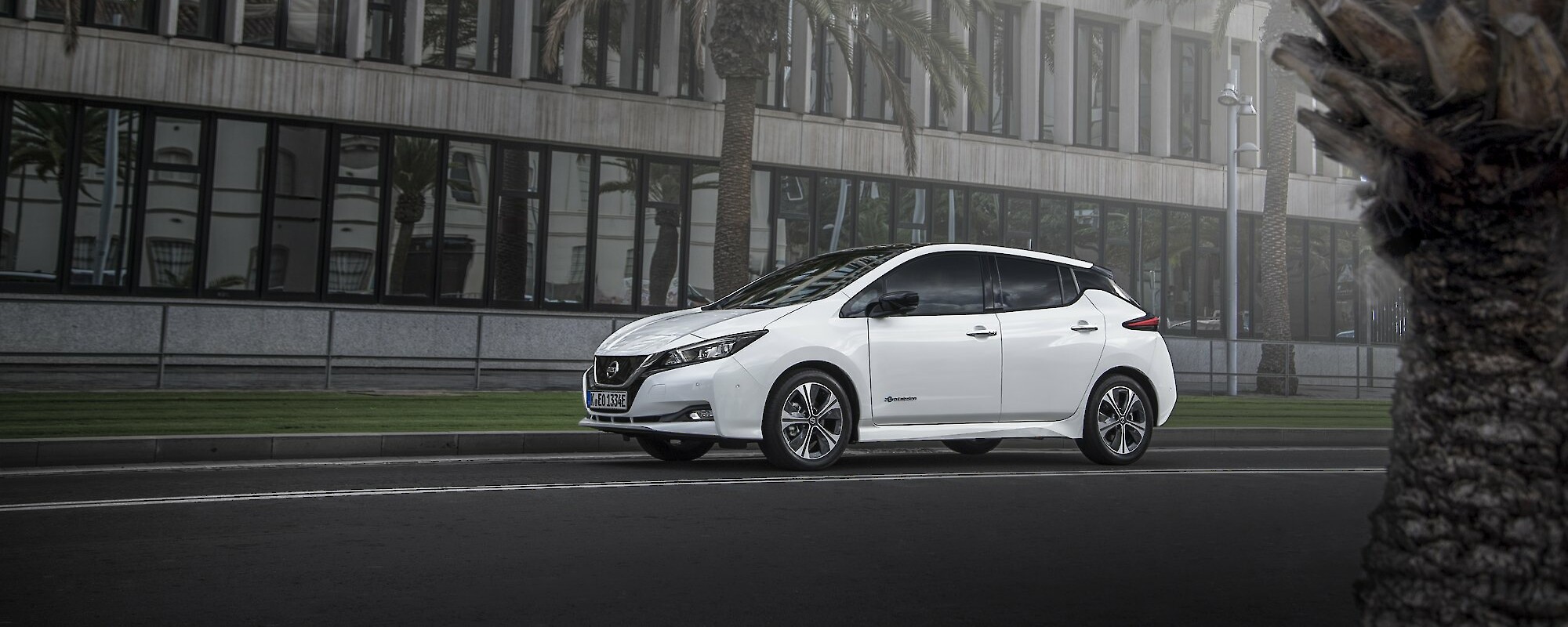 Fehér Nissan Leaf halad a városban